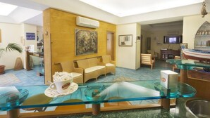 Un vestíbulo de hotel con una mesa de centro de vidrio, un sofá, un televisor y un cuadro en la pared.