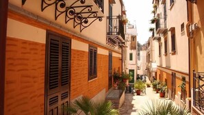 Una calle estrecha con edificios que tienen balcones y macetas.