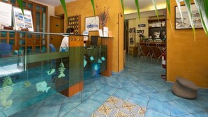 Un área de recepción con un mostrador de cristal, decoraciones de peces y un escritorio de madera.