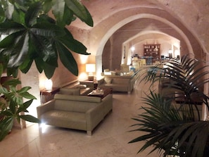 A spacious lobby with a seating area, a coffee table, and a lamp.