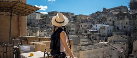 Un balcón con vistas a un paisaje urbano histórico, con edificios de piedra y cielo despejado.