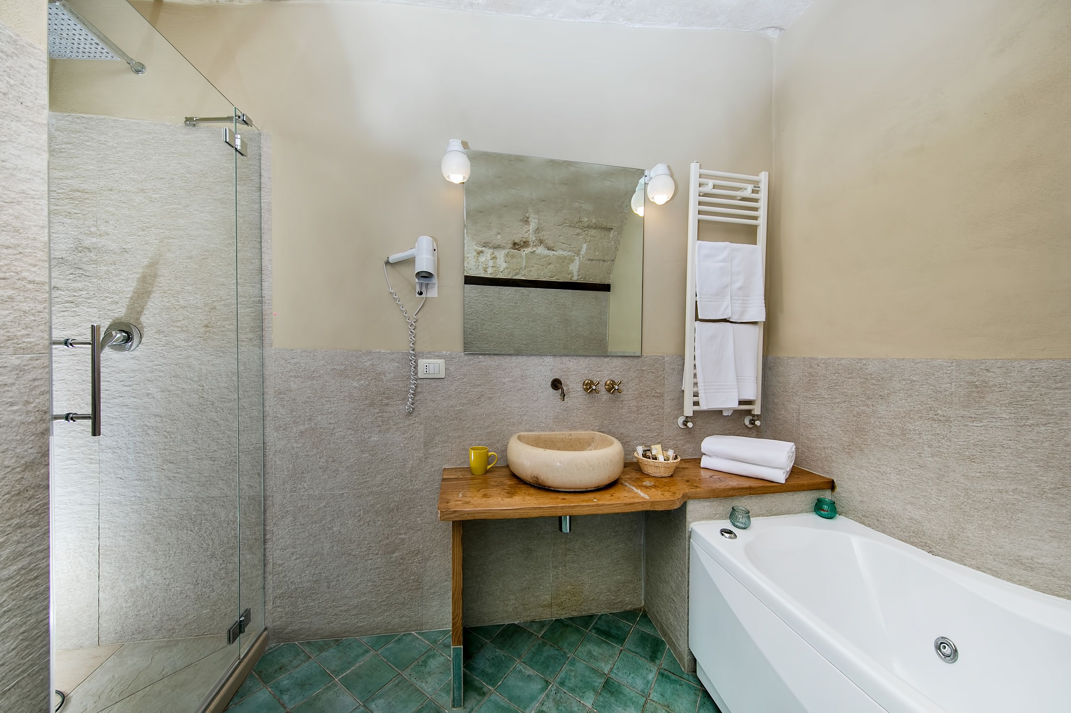 Ein Badezimmer mit Duschkabine aus Glas, einem Holzkosmetikschrank mit Waschbecken, einem Spiegel und einer weißen Badewanne.
