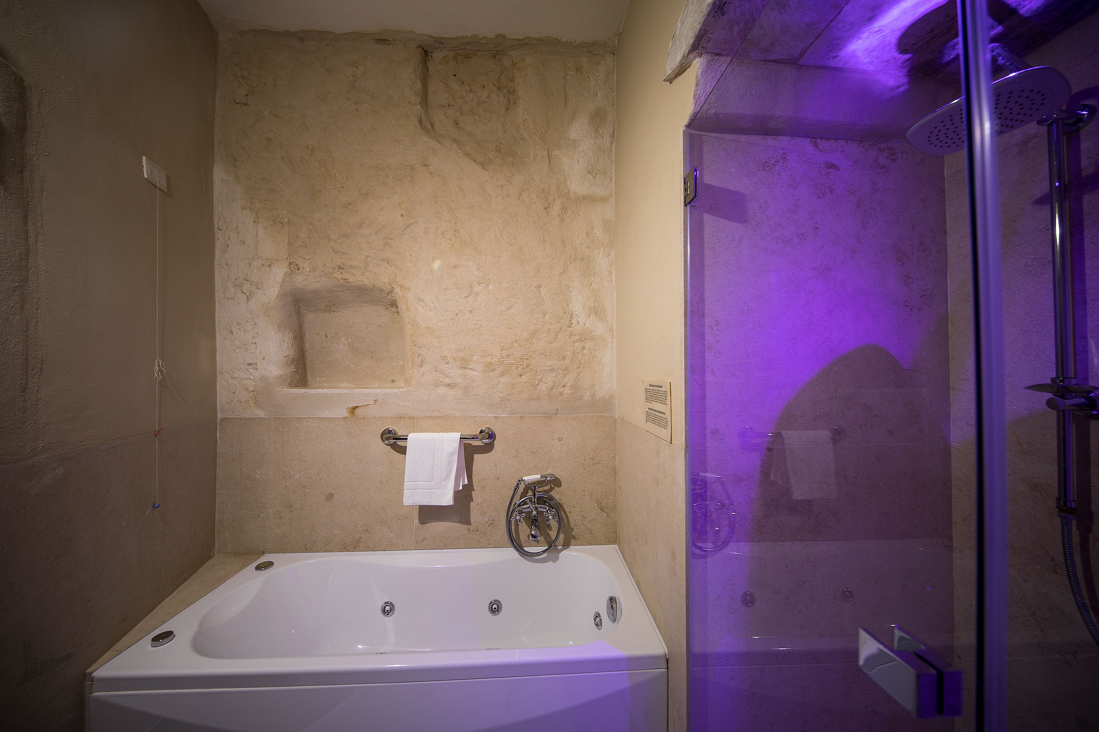 A bathroom with a bathtub, a glass-enclosed shower, and a towel rack.