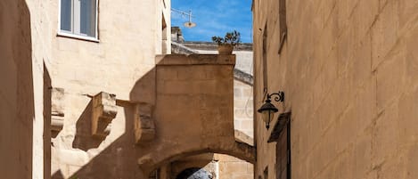 A narrow alleyway with cobblestone pavement, stone buildings, and a small archway.