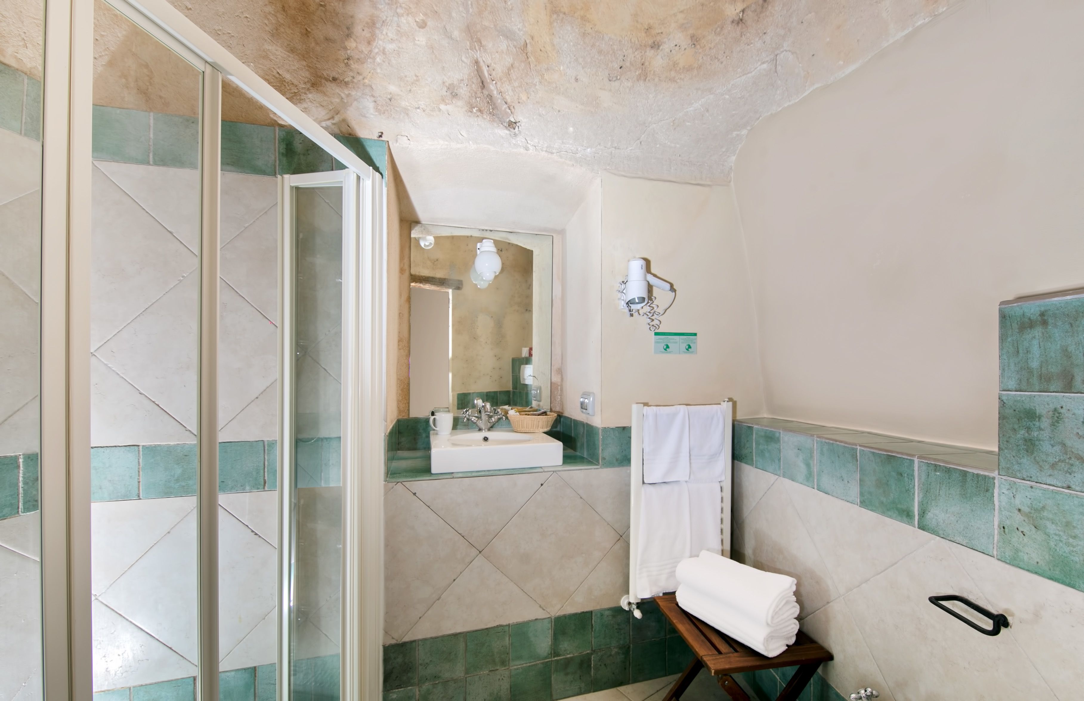 Une salle de bain avec une porte de douche en verre, un lavabo avec un miroir et un porte-serviettes.