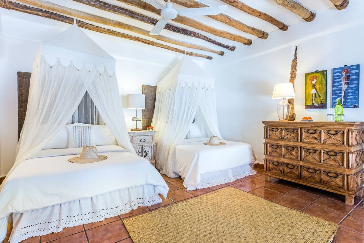 Un dormitorio con dos camas, un aparador de madera y un ventilador de techo.