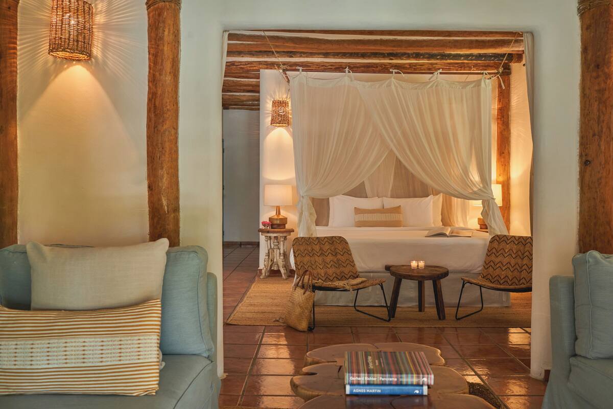 Una habitación acogedora con una cama, un sofá, una silla y una mesita.