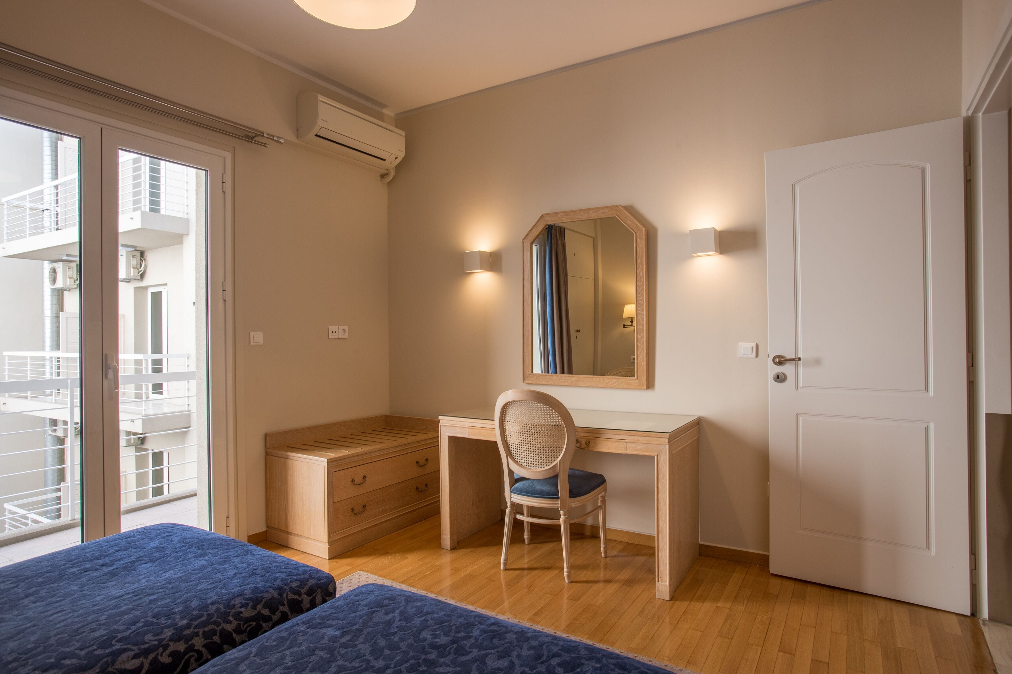 Un dormitorio con un escritorio de madera, una silla, una cama y un ventanal grande.