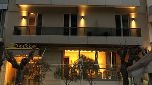 Ett hotell med flera våningar, balkonger, en flagga och en skylt med texten ”Delice”.