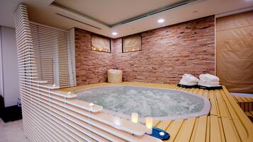 Un spa moderno con un jacuzzi, bancos de madera y una pared de ladrillo.