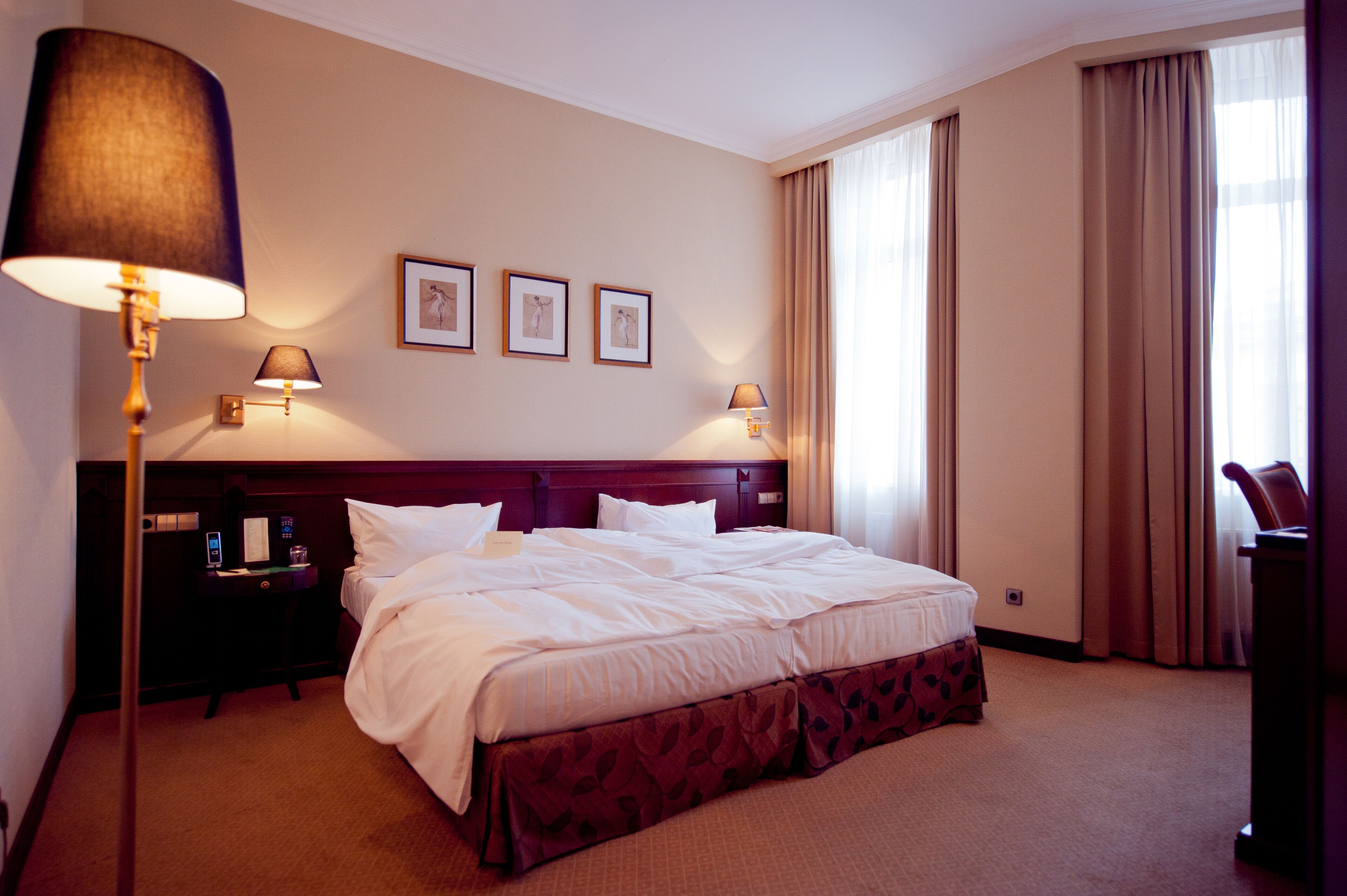 A hotel room with a large bed, two bedside tables, a nightstand, and a lamp.