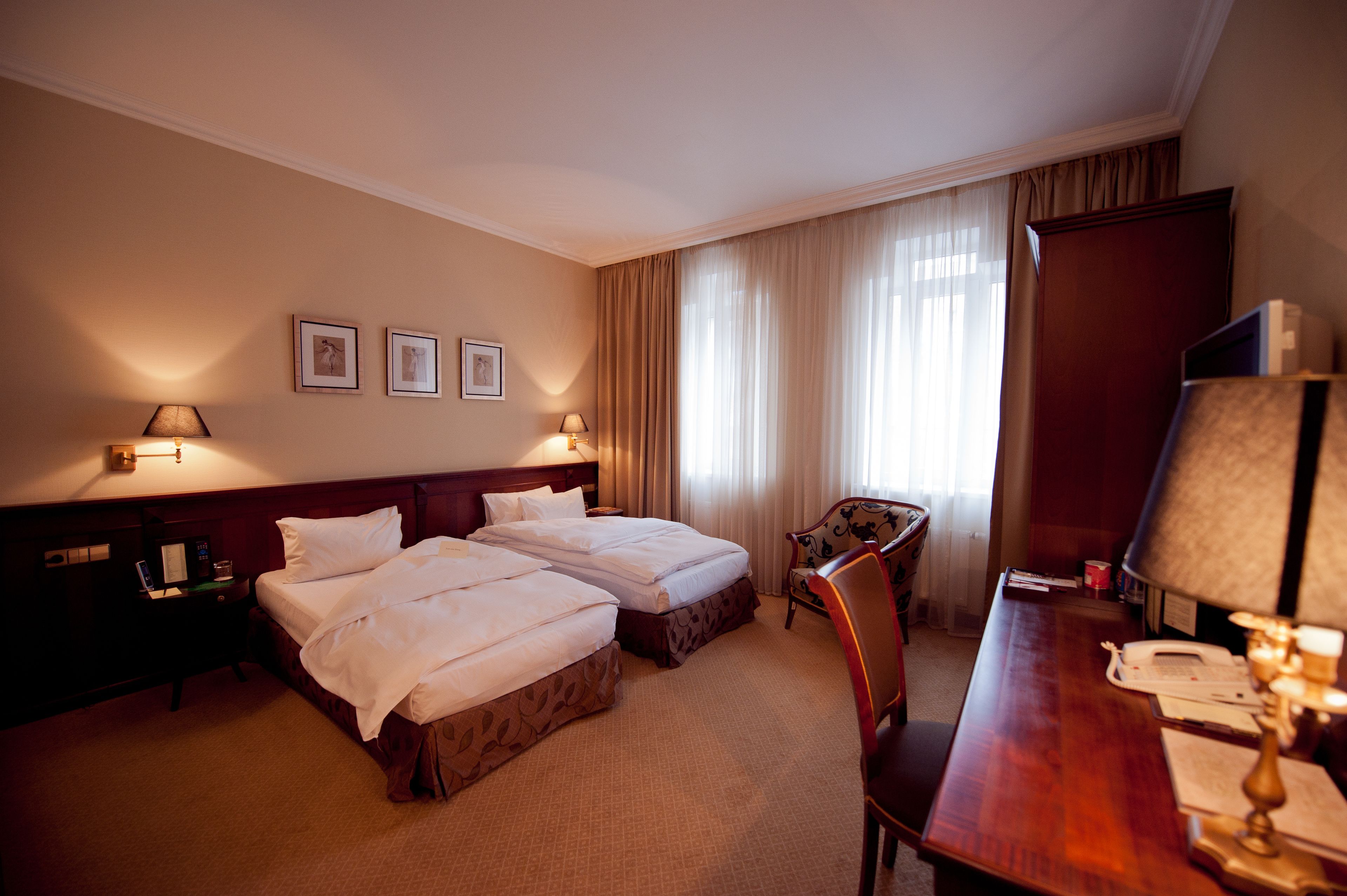 Een hotelkamer met twee bedden, een bureau, een stoel, een televisie en een lamp.