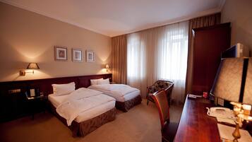 Een hotelkamer met twee bedden, een bureau, een stoel, een televisie en een lamp.