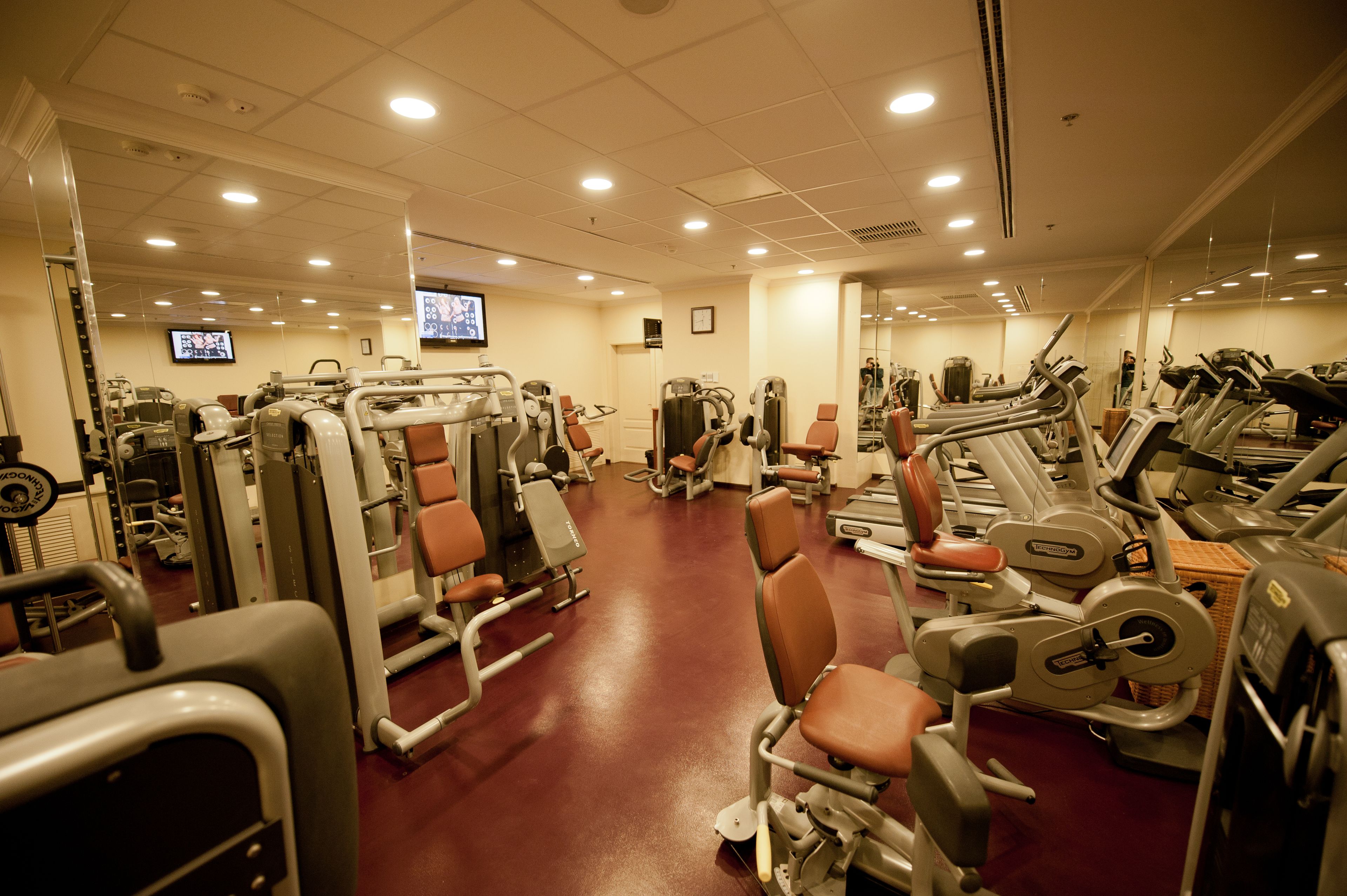 A gym with various exercise machines, a television, and a mirror on the wall.