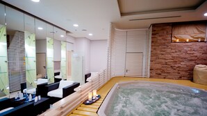 Une salle de spa moderne dotée d’une grande baignoire, d’un long banc et d’une rangée d’éviers et de miroirs.