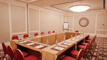 A conference room with a long table, red chairs, water bottles, and a whiteboard.