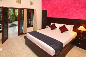 A hotel room with a bed, a nightstand, a lamp, and a sliding glass door leading to an outdoor area.