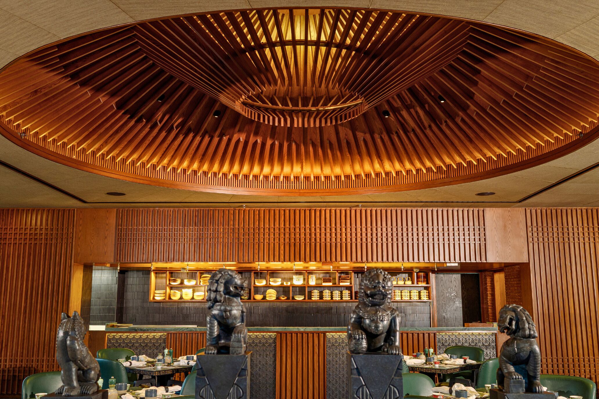 Een restaurantinterieur met een houten plafond, een toonbank met diverse artikelen en leeuwenbeeldjes op de tafels.