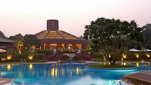 A modern hotel with a swimming pool, a well-lit entrance, and a landscaped garden area. - The Westin Sohna Resort & Spa (Sohna)