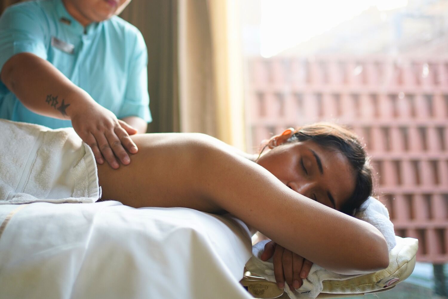 Iemand ontvangt een massage in een kamer met een raam en een bakstenen muur.
