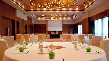 A conference room with round tables, chairs, and a large screen at the front.