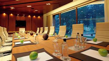 A conference room with a long table, multiple chairs, and a large window with a view of trees.