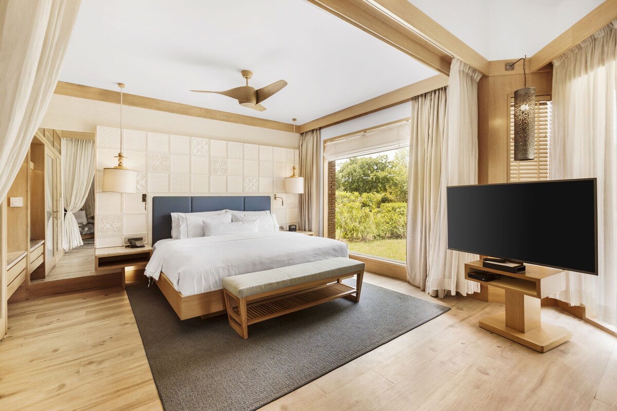 Un dormitorio moderno con una cama grande, televisión y vistas al exterior.
