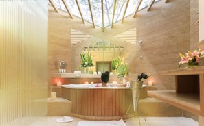 Un baño moderno con una bañera de madera, un espejo grande y un tragaluz.