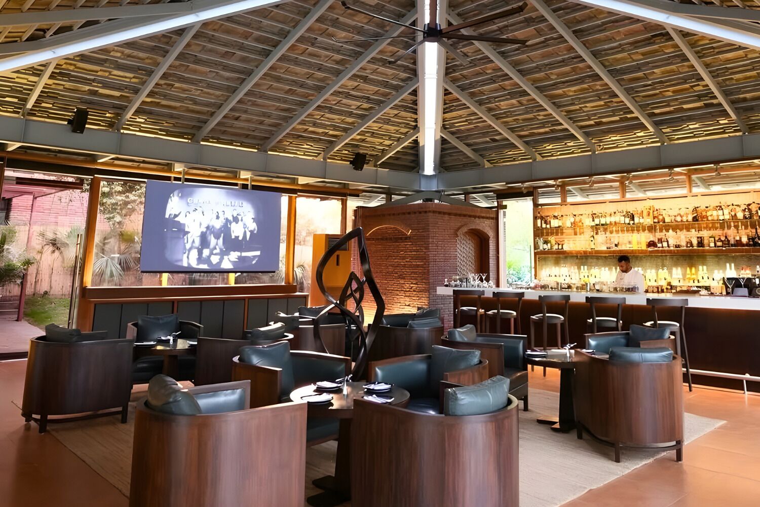 A bar area with seating, a television screen, and a bartender.