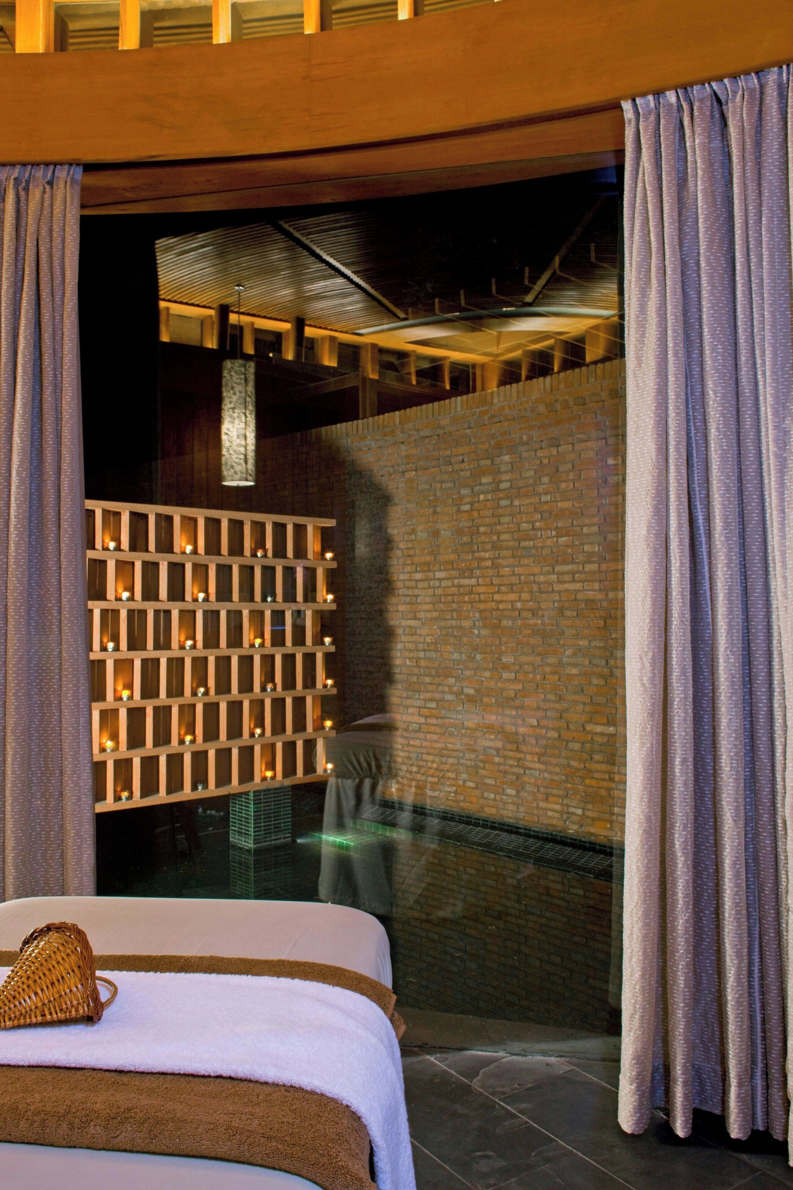 Habitación de hotel con cama, cesta tejida y vista a un edificio a través de una puerta de vidrio.