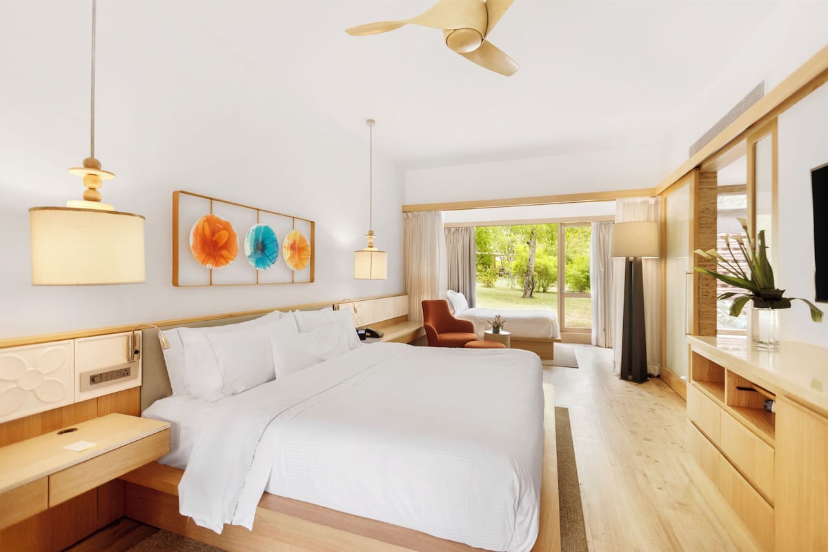 A modern hotel room with a large bed, a desk, a chair, and a TV.