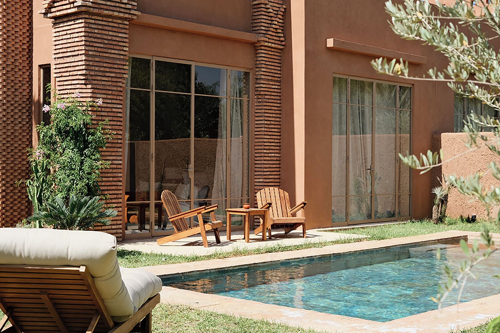 Una casa moderna con piscina, mobiliario de exterior y amplias ventanas.