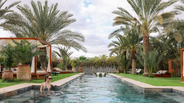 Una piscina con muelle de madera y palmeras.