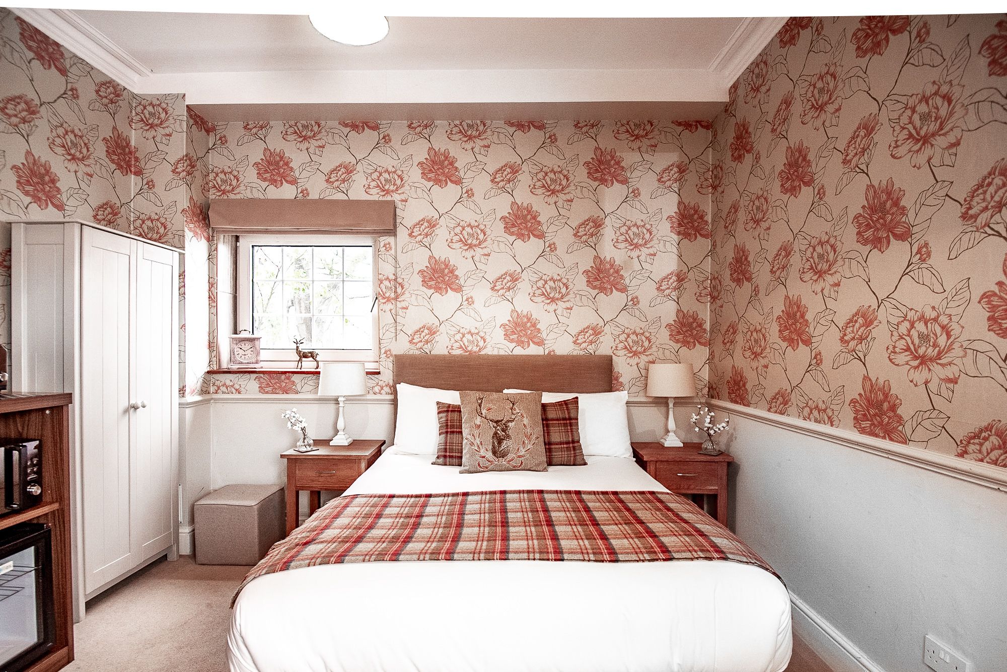 Een slaapkamer met een bed, twee nachtkastjes, een kledingkast en een raam.