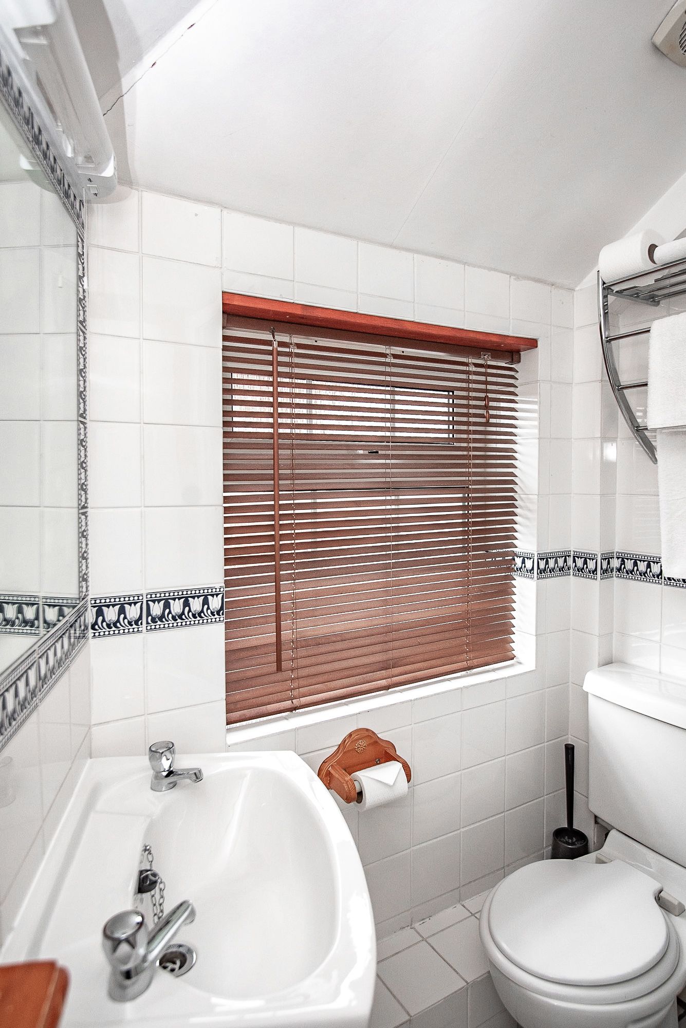 A bathroom with a sink, toilet, and window with blinds.