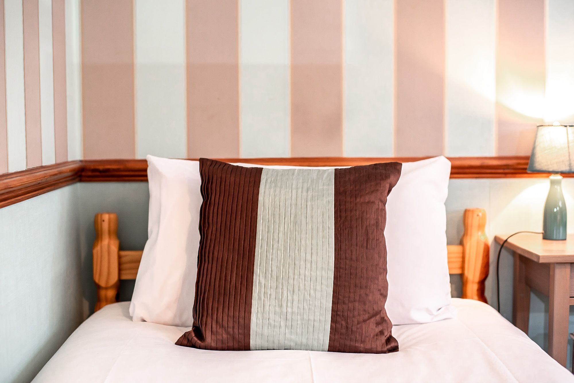 A bed with a striped pillow and a wooden headboard.
