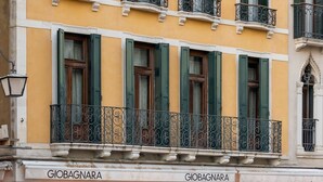 A building with yellow facades, green shutters, and ornate balconies.