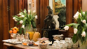 A breakfast table with various food items, a statue, and a painting.