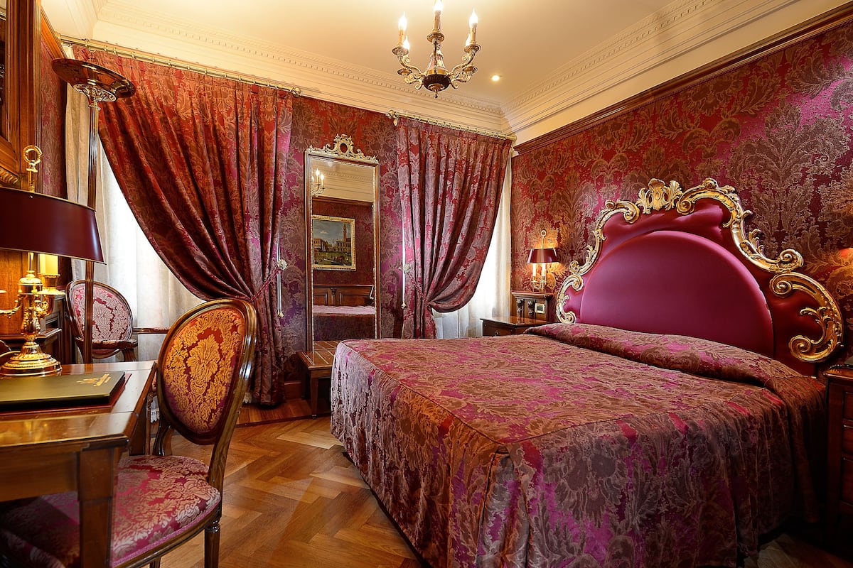 A luxurious bedroom with a large bed, ornate curtains, and classic furniture.