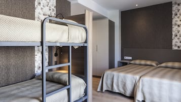 A modern hotel room with bunk beds, a large bed, and a wardrobe.