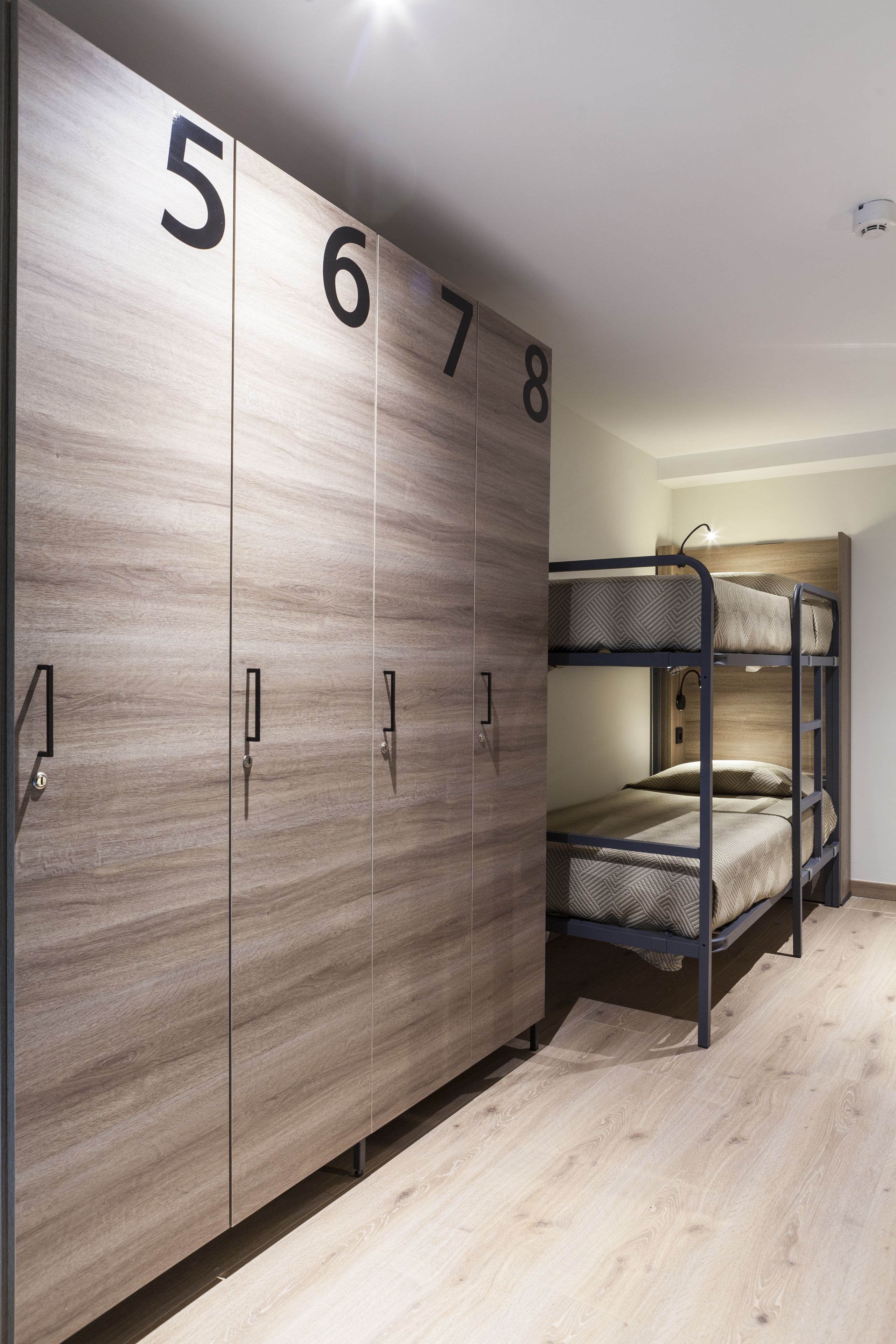 Ein Etagenbett mit Kopfstütze, ein Kleiderschrank mit Nummern und ein Holzboden.