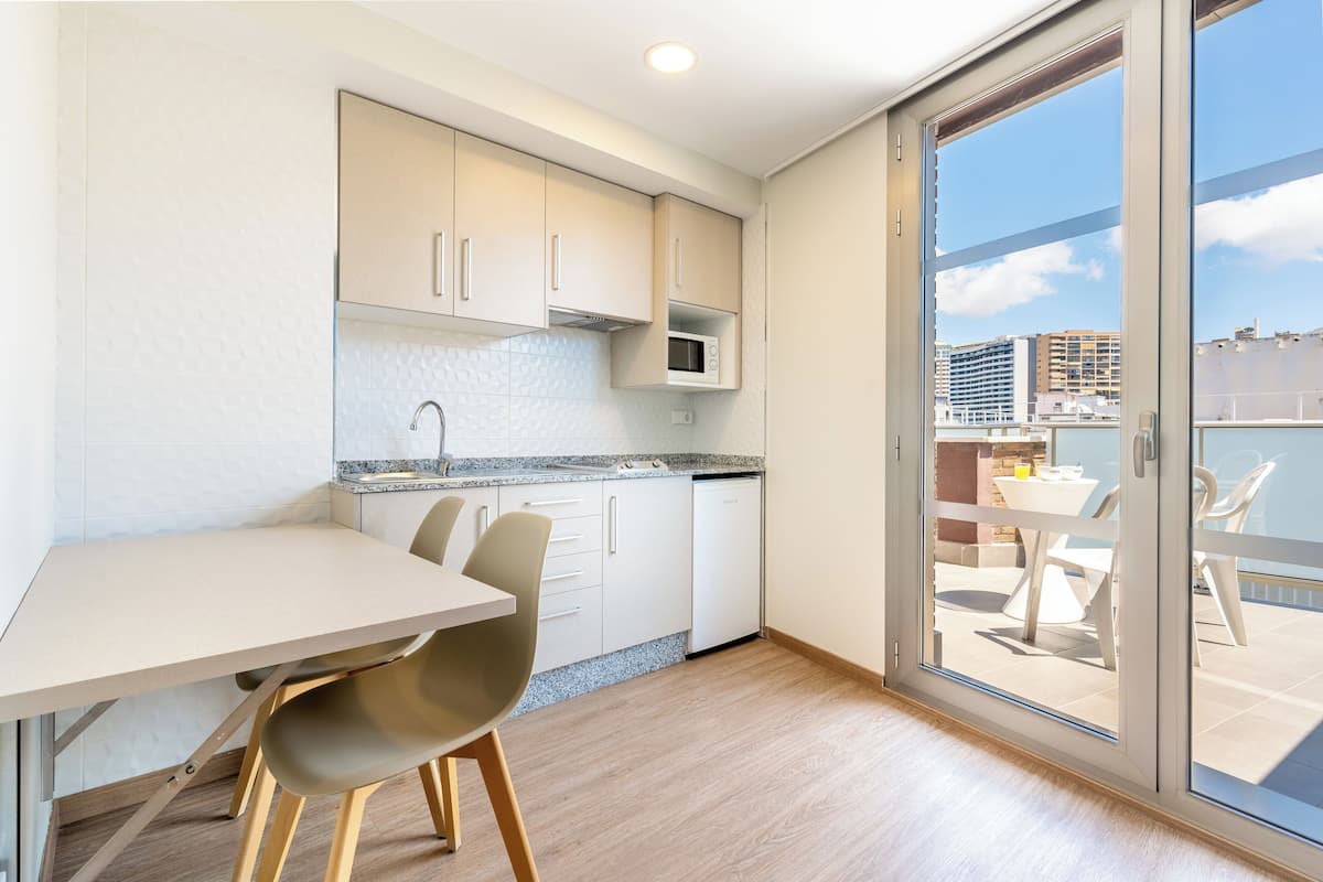 A modern kitchen with a dining area, a built-in microwave, and a view of the city through large glass doors.