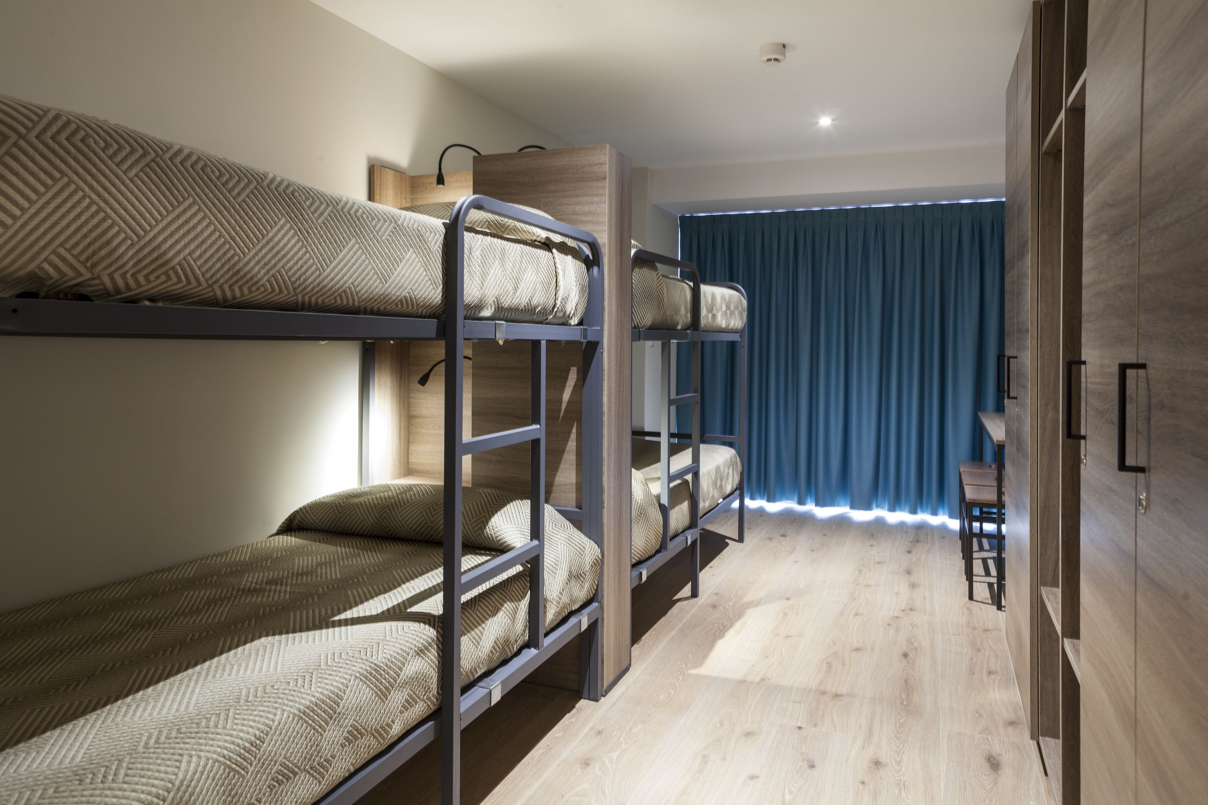 Una habitación con literas, un armario de madera y una mesita.