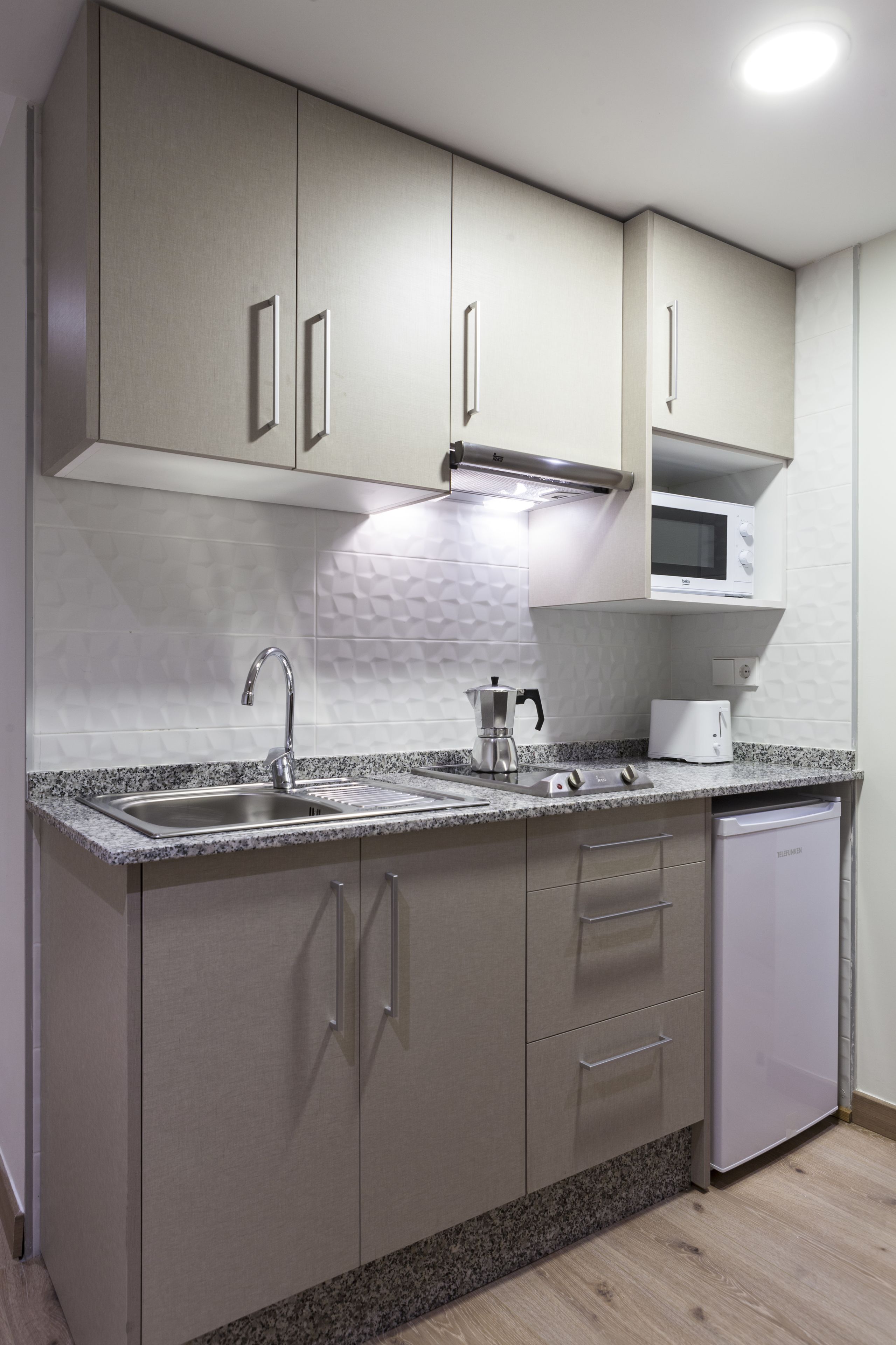 A modern kitchen with a granite countertop, stainless steel sink, and white appliances.