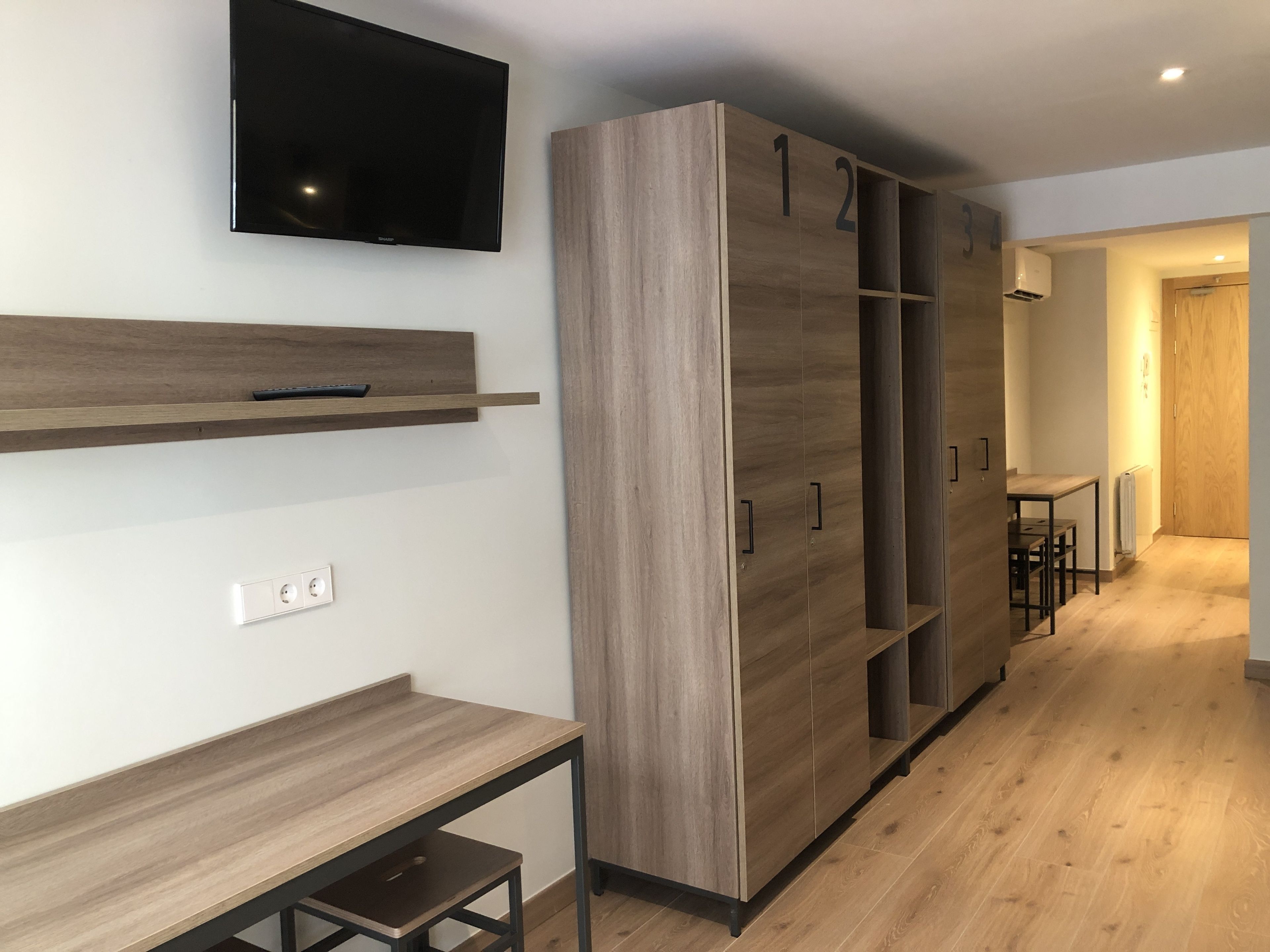 A modern interior with a wooden wardrobe, a mounted TV, and a small table.
