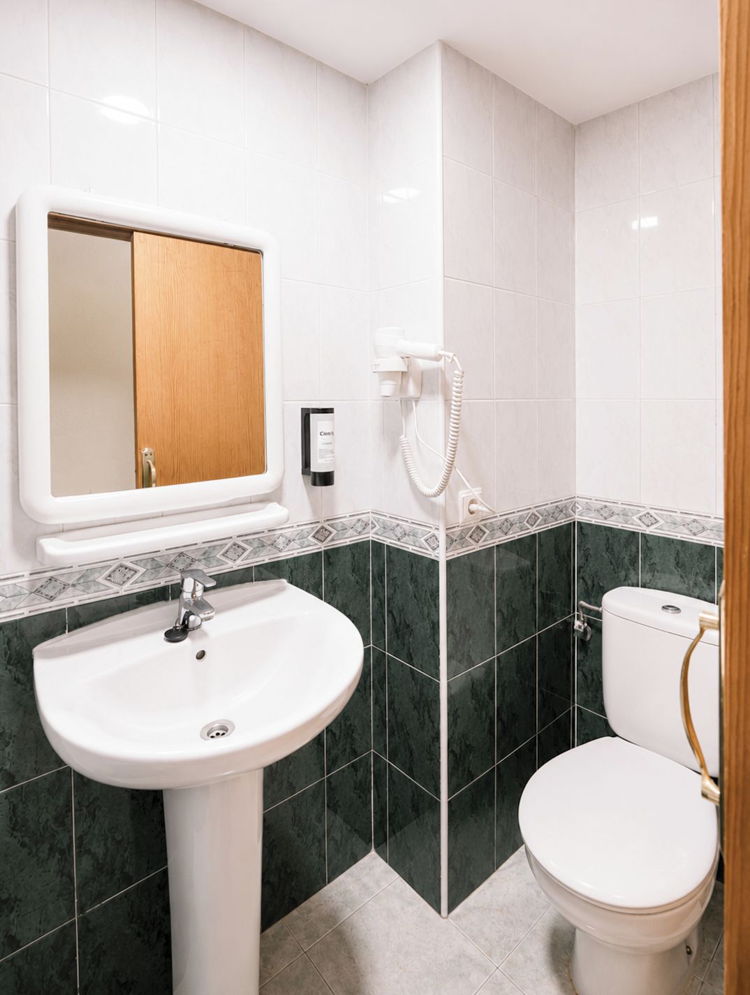 A bathroom with a pedestal sink, a toilet, and a shower area.