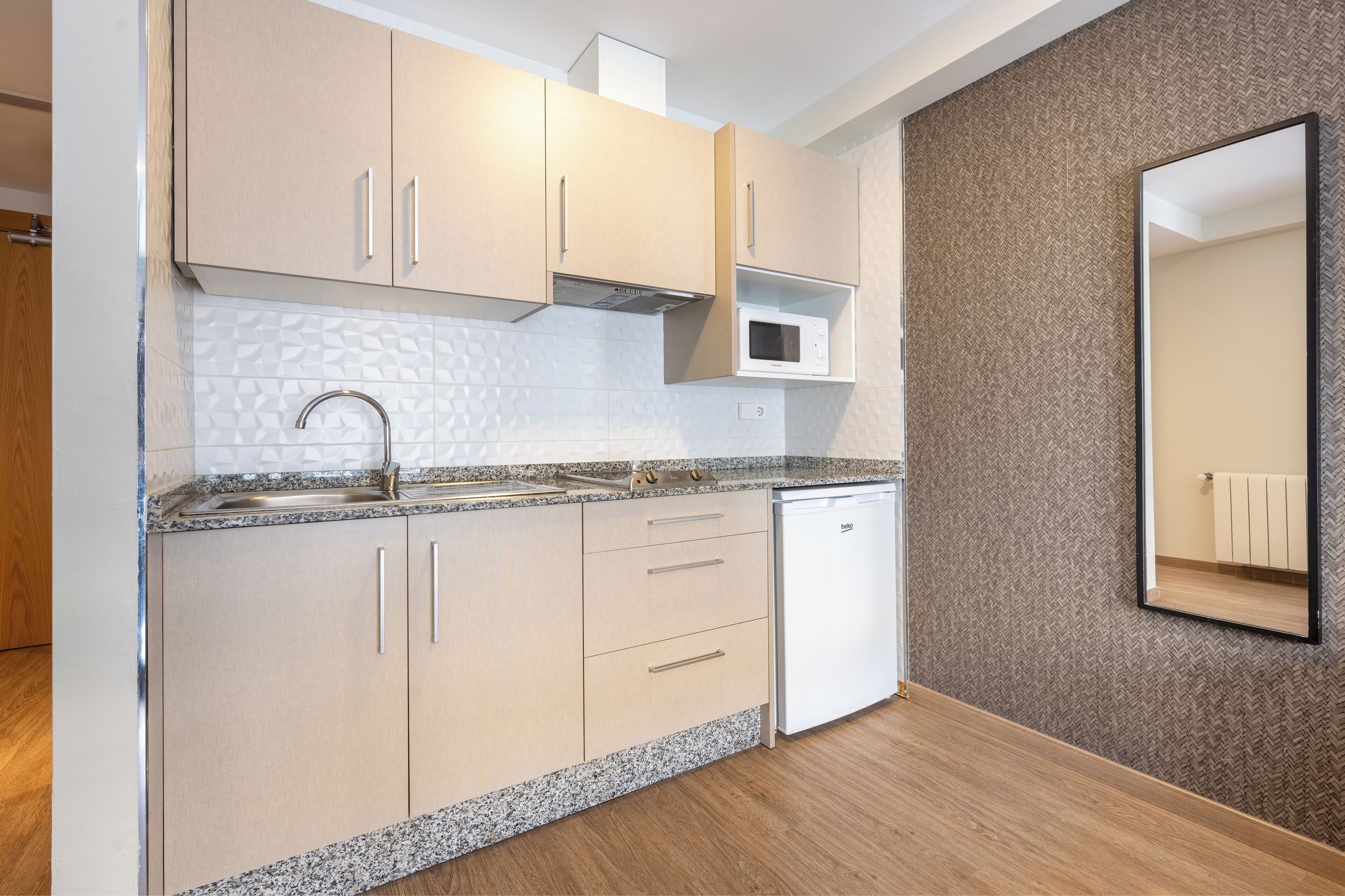 A modern kitchen with light wood cabinets, a granite countertop, a built-in microwave, and a dishwasher.