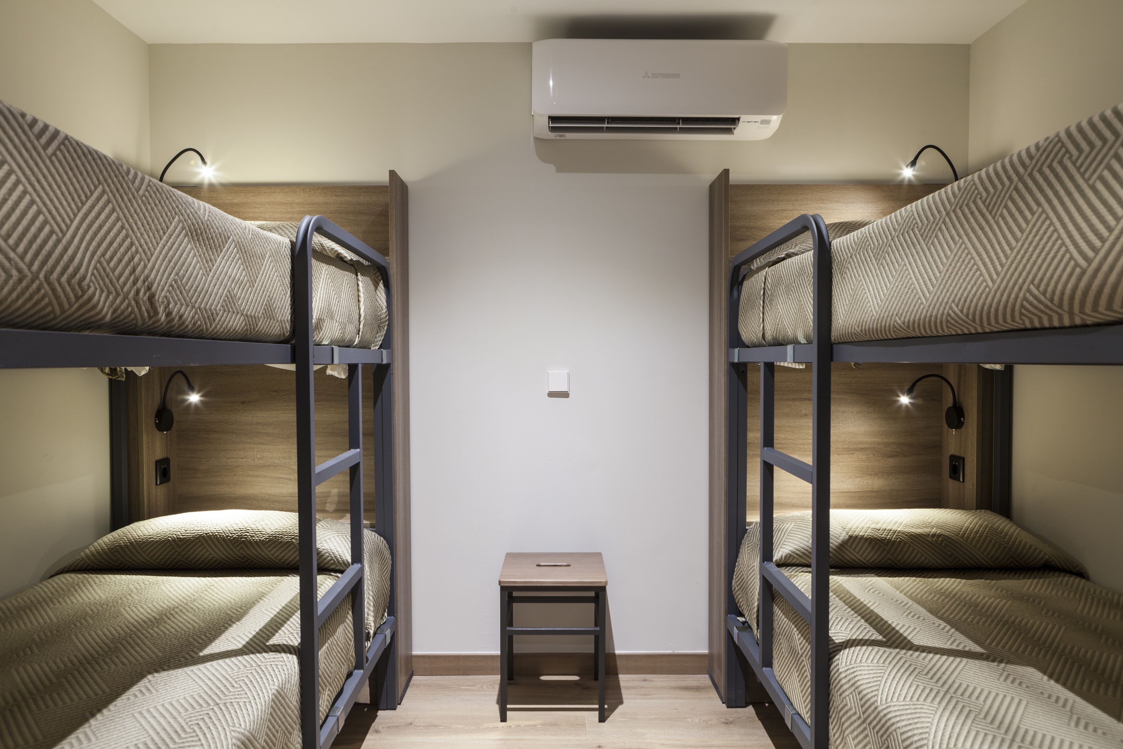 A room with bunk beds, a small table, and an air conditioning unit.