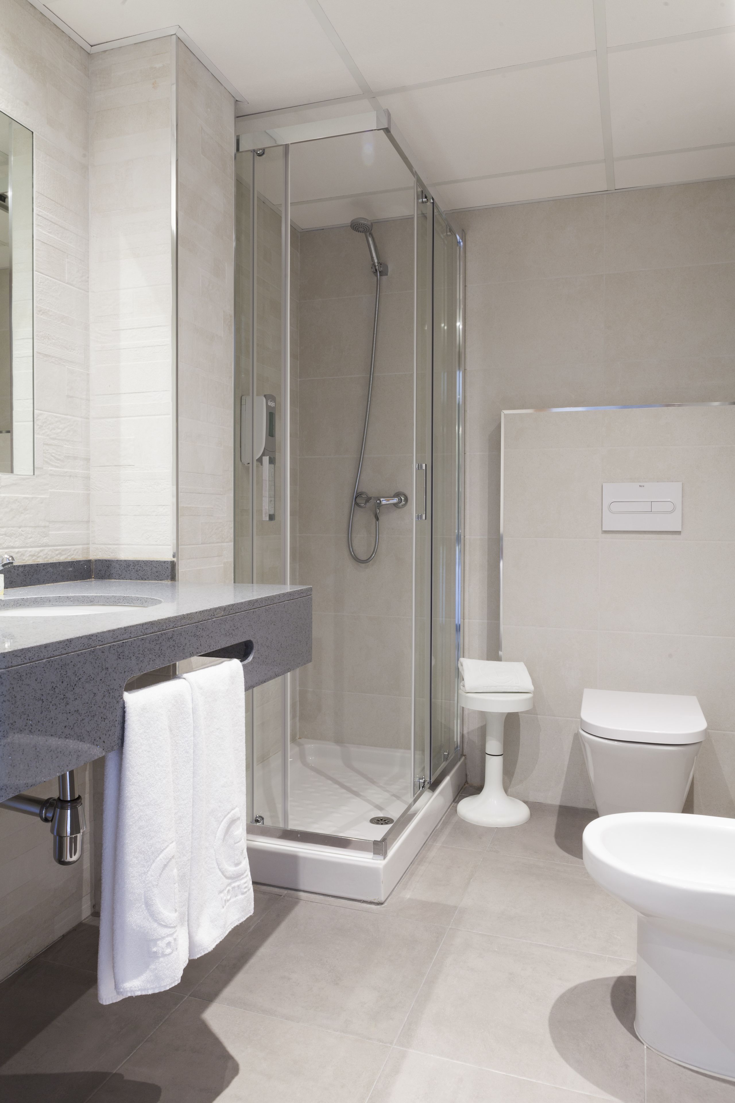 Une salle de bain moderne avec une douche à parois de verre, un lavabo blanc et des toilettes.