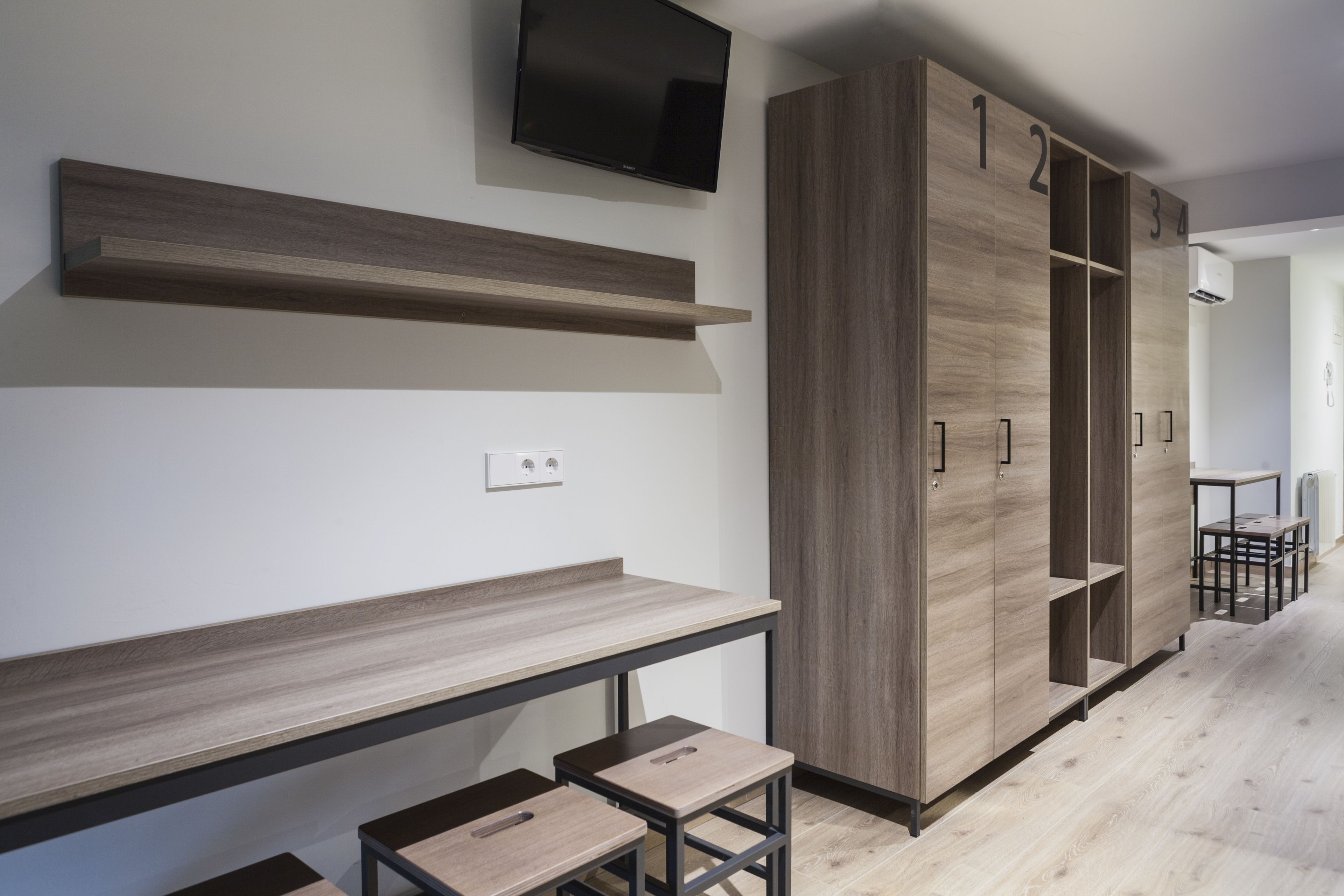 A modern room with built-in wooden shelving, a desk, and a seating area.